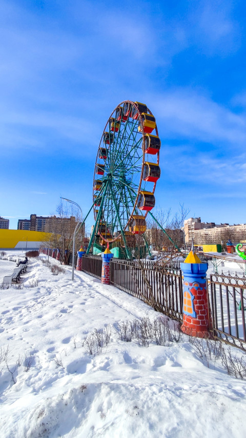 Аттракцион за оградой и заснеженной прогулочной зоной
