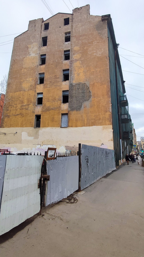 Старая пятиэтажная стена заброшенного здания с повреждённой штукатуркой