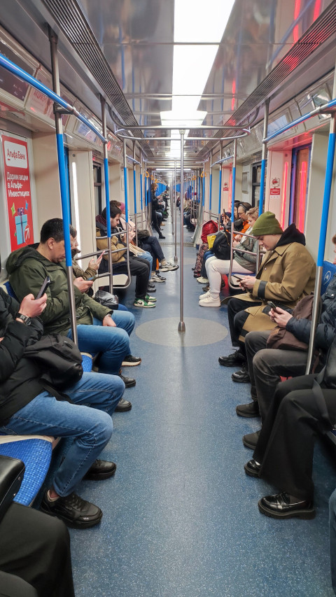 Группа людей сидит в поезде метро рядом друг с другом