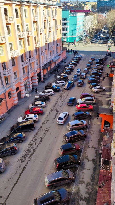Дорога с припаркованными автомобилями и жилыми домами в центре города