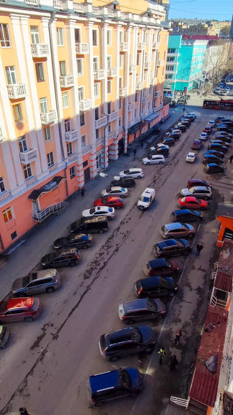 Городская улица с жилыми домами и припаркованными автомобилями