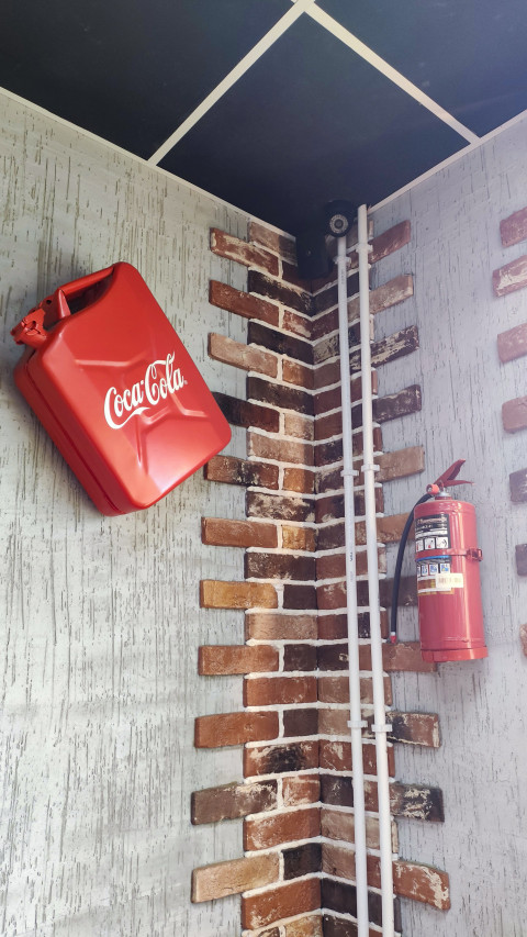 Красная канистра с логотипом Coca-Cola и огнетушитель на стене