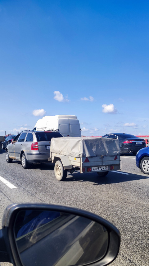 Легковой автомобиль с прицепом в потоке на скоростной трассе; вид из салона
