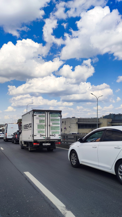 Поток автомобилей на городской магистрали с фургоном в полосе