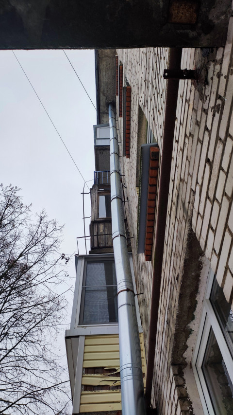 Вертикальный вид фасада старого жилого дома с водосточной трубой