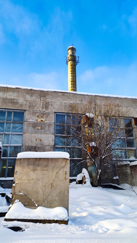 Бетонный фасад и дымовая труба на территории старого цеха