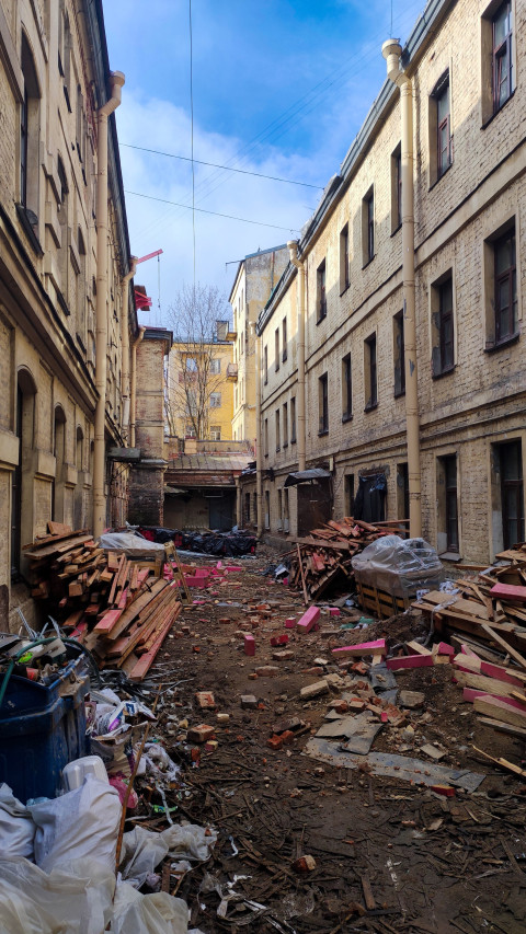 Двор старого здания с мусором и строительными материалами