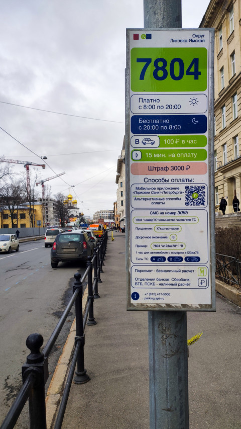 Парковочный знак 7804 на фоне транспортного потока и городской застройки