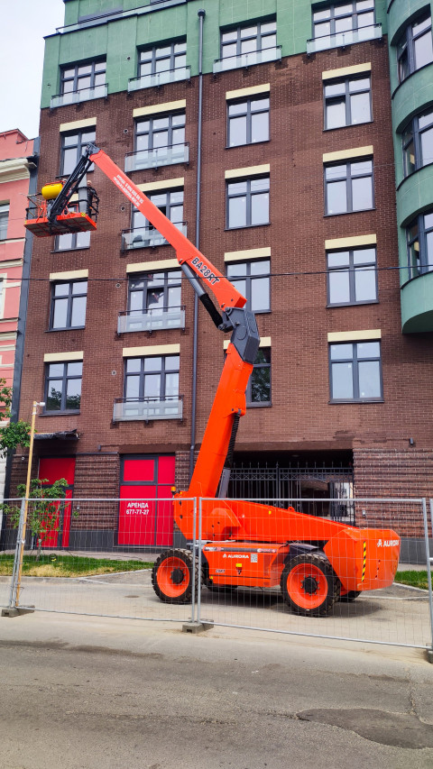 Телескопический подъёмник AURORA у кирпичного фасада во время высотных работ