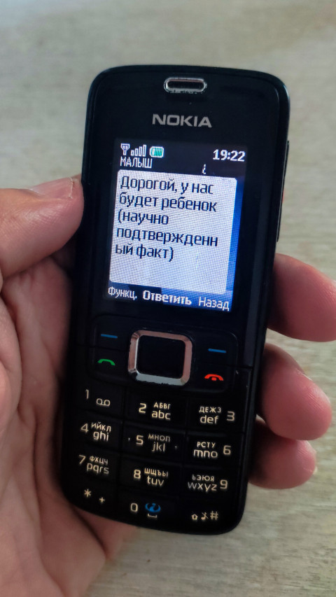 SMS на экране Nokia с текстом о будущём ребёнке и подписью контакта «МАЛЫШ»