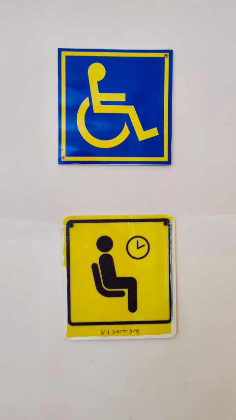 Знаки доступности и приоритетного ожидания с тактильной подписью на стене