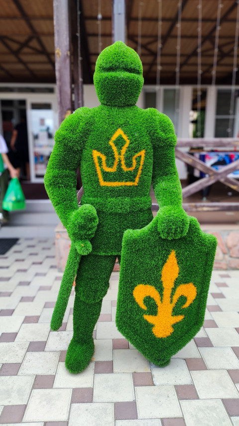 Топиарная фигура рыцаря с мечом и щитом на плиточной площадке