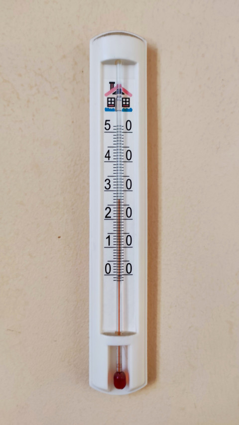 Настенный термометр со шкалой температуры на светлой стене