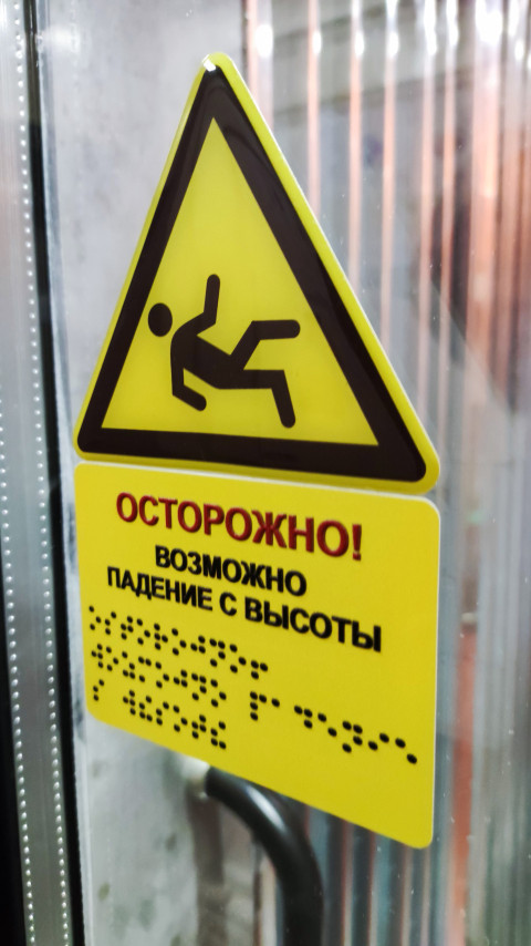 Желтый знак осторожности на стеклянной двери