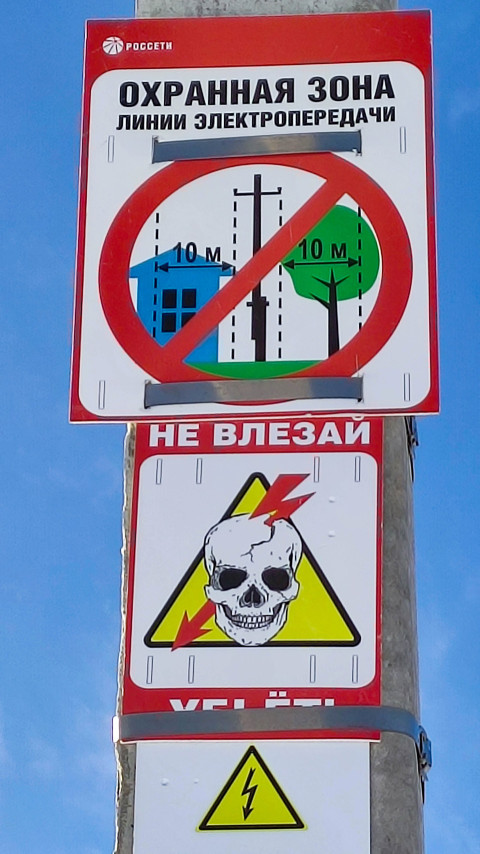 Знаки безопасности в охранной зоне линии электропередачи с предупреждением о запрете доступа