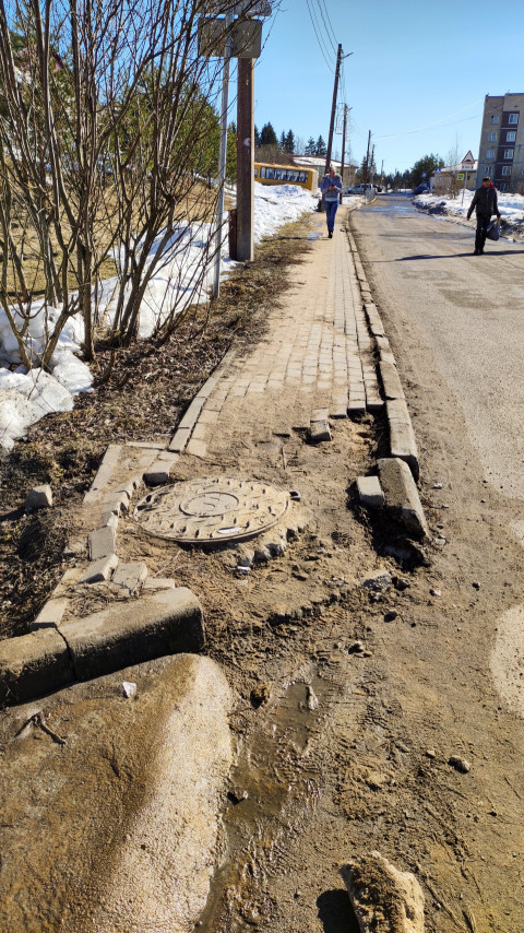 Разрушенный тротуар возле дороги в небольшом городе