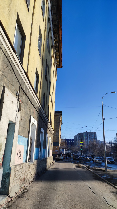 Пешеходный тротуар вдоль жилого дома и оживленной дороги в городе