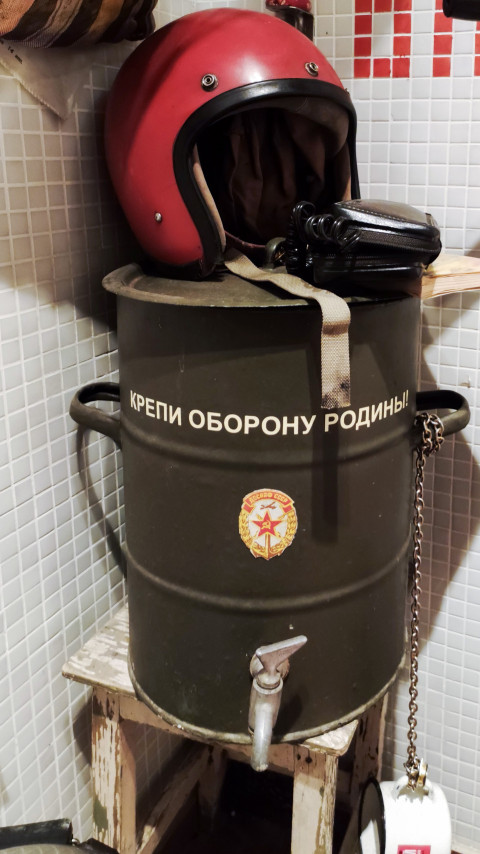Шлем и военный бачок с лозунгом на фоне плитки
