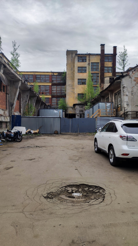Общий вид двора с заброшенным зданием и припаркованными машинами
