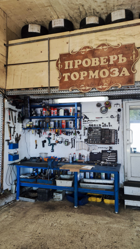 Верстак с инструментами и табличкой «Проверь тормоза» в автосервисе