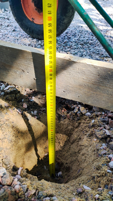 Измерение глубины ямы на строительной площадке с показателем около 50 см