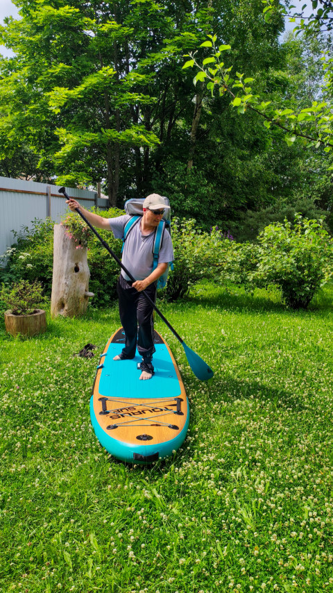Мужчина с веслом на SUP-доске в саду