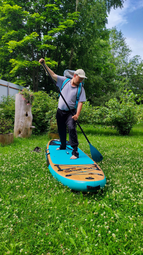 Мужчина на SUP-доске с веслом в саду