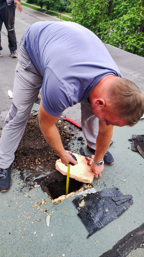 Рабочий измеряет высоту основания на крыше здания
