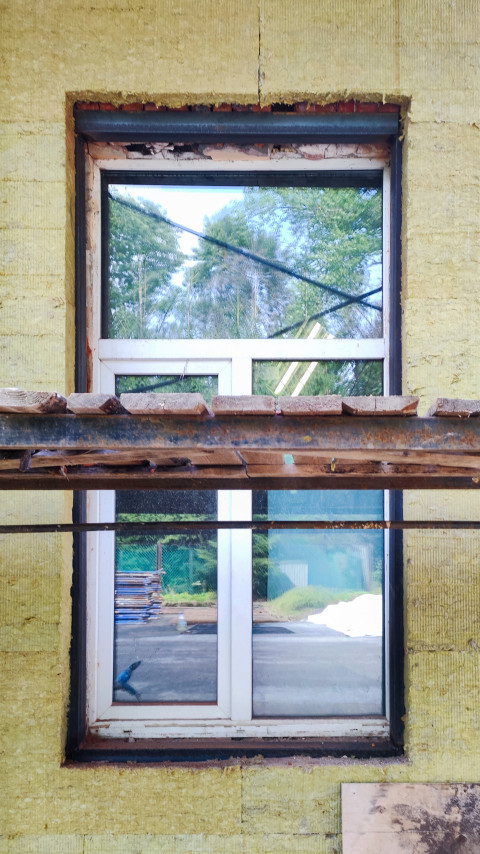 Утеплённый фасад здания с пластиковым окном и строительными лесами