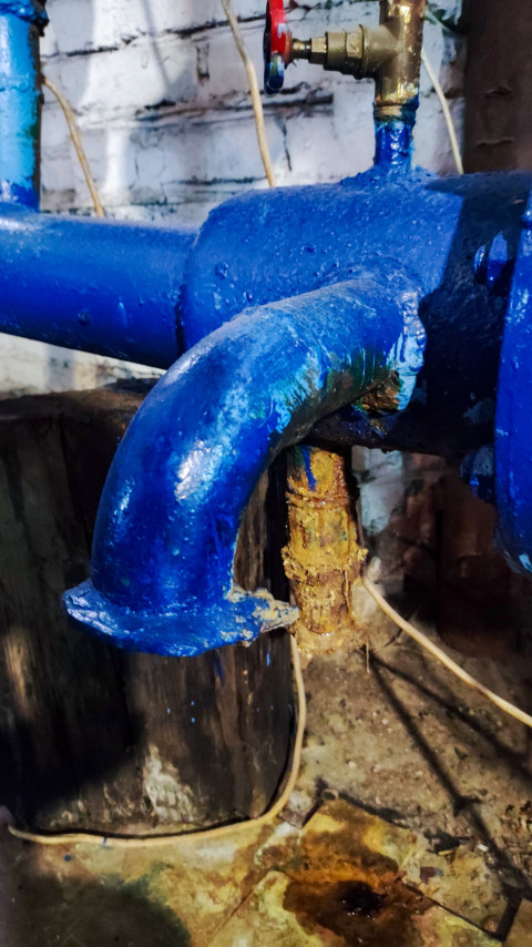 Отвод водопроводной трубы с вентилем и следами коррозии