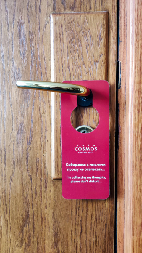 Дверная табличка «Cosmos Hotel» на ручке гостиничного номера