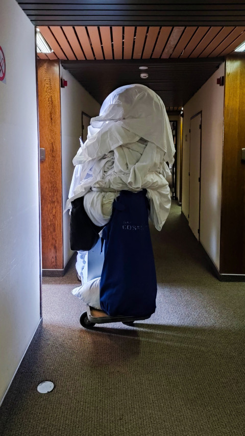 Гостиничная уборочная тележка с бельём в коридоре отеля