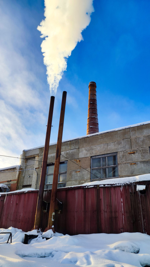 Рабочие дымоходы с выбросом пара у производственного корпуса