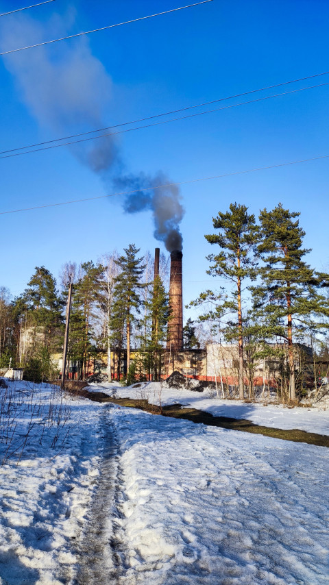 Заводская труба с дымом зимой на фоне синего неба