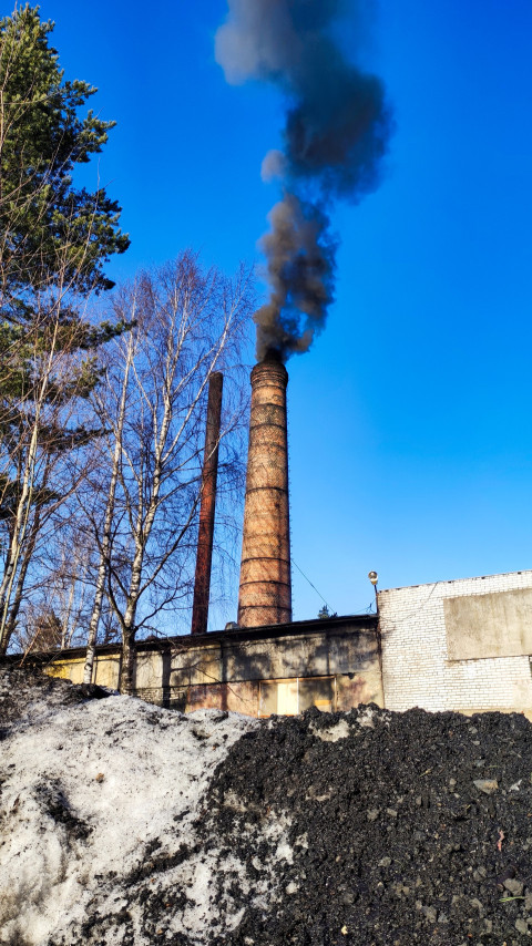 Кирпичная дымовая труба с черным дымом и зимним пейзажем