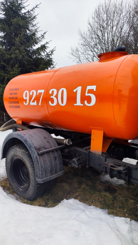 Оранжевая цистерна грузовика на фоне ели и зимнего неба