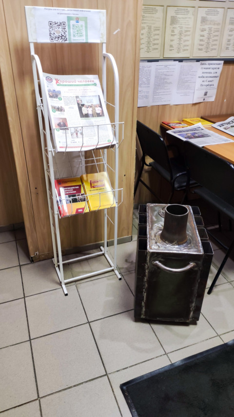 Стойка с печатными материалами и металлическая емкость в административном интерьере