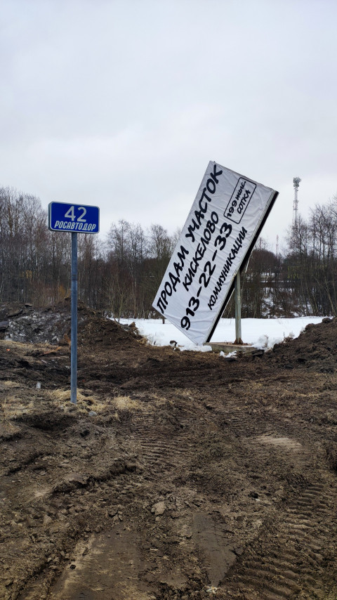 Наклонённый рекламный щит и знак «Росавтодор 42» на зимней дороге