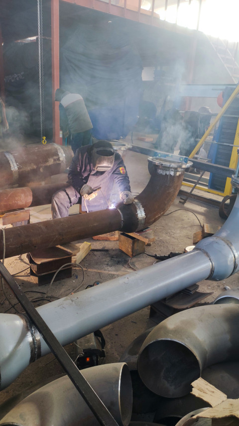 Сварщик выполняет монтаж стальных трубопроводов