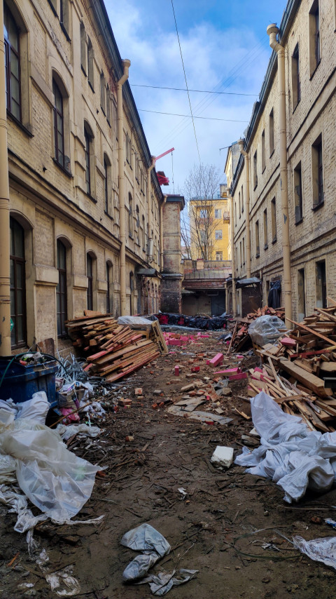 Узкий проход между историческими зданиями с остатками стройматериалов