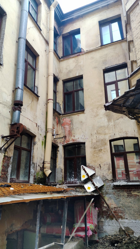 Внутренний двор с водосточными трубами и повреждённой штукатуркой