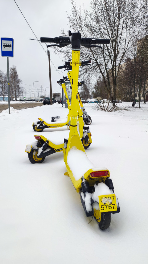 Электросамокаты «Яндекс Go» на фоне зимнего городского пейзажа