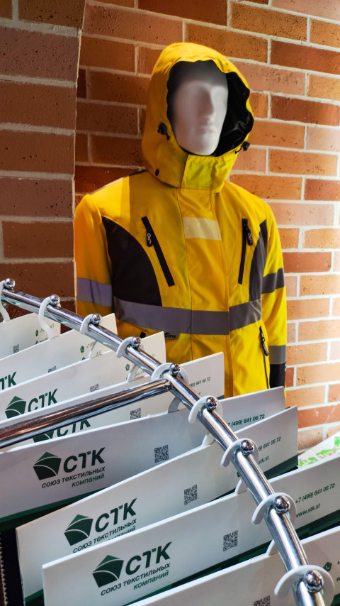 Манекен в жёлтой защитной куртке на выставочном стенде текстильной компании