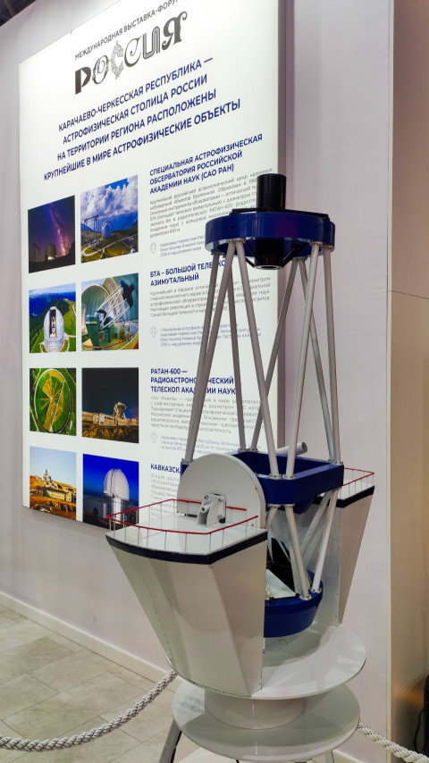 Макет телескопа на фоне стенда об астрофизических объектах региона