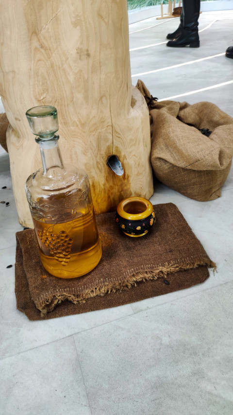 Стеклянная бутыль с напитком у деревянного пресса