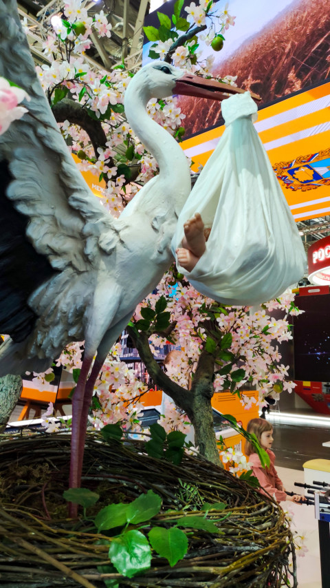 Декоративная инсталляция аиста с узлом на фоне цветущих деревьев
