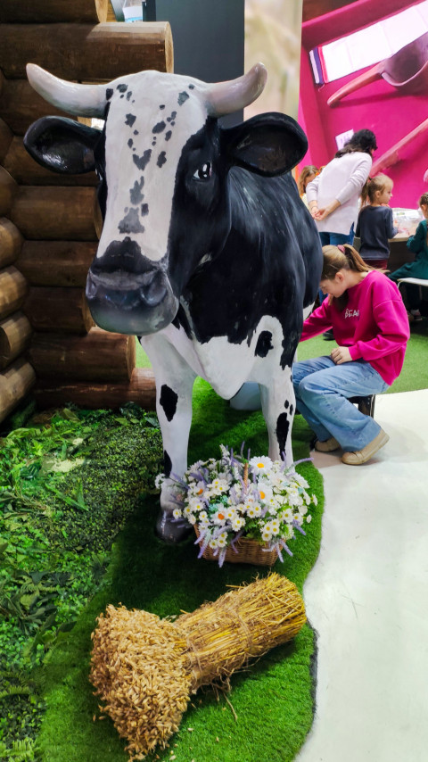 Макет коровы и посетитель у интерактивной зоны на выставке