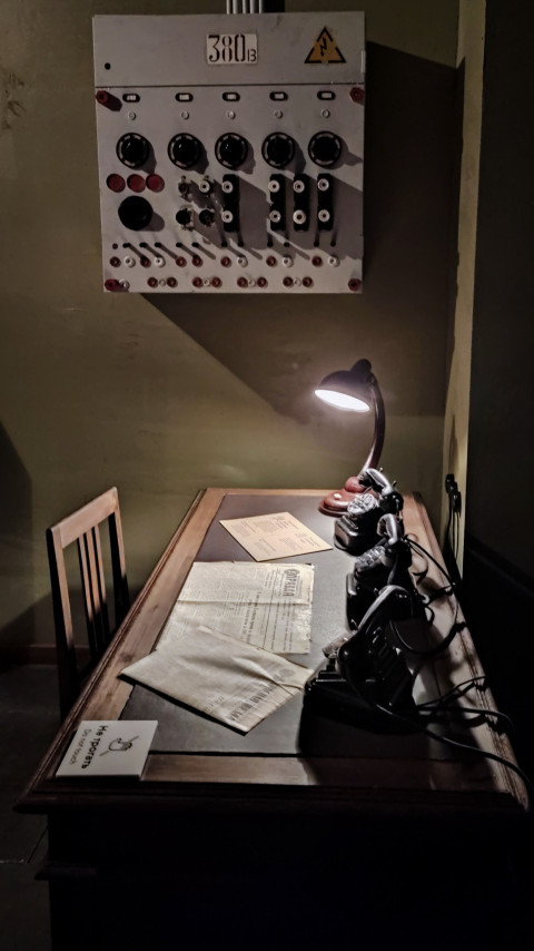 Диспетчерский стол с документами и ретротелефонами под настенной панелью управления