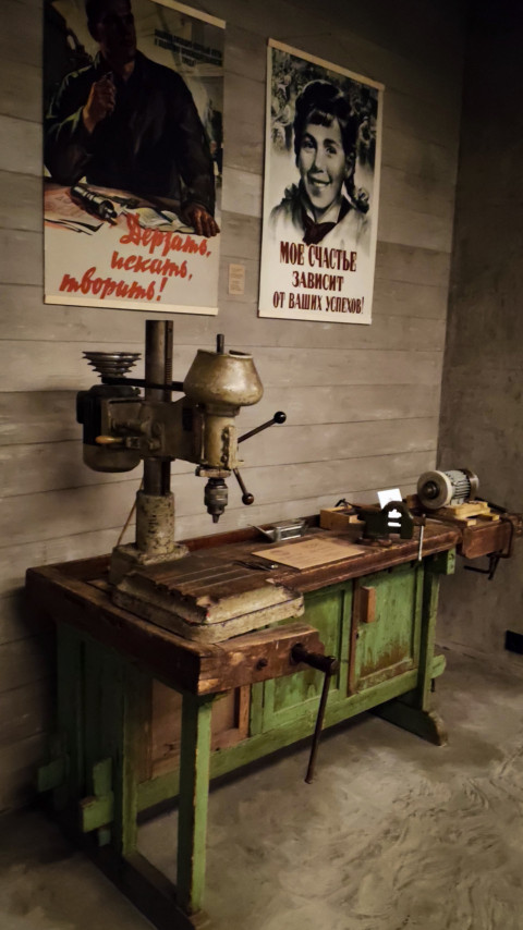 Рабочий стол с дрелью и советскими агитационными плакатами в павильоне «Атом»