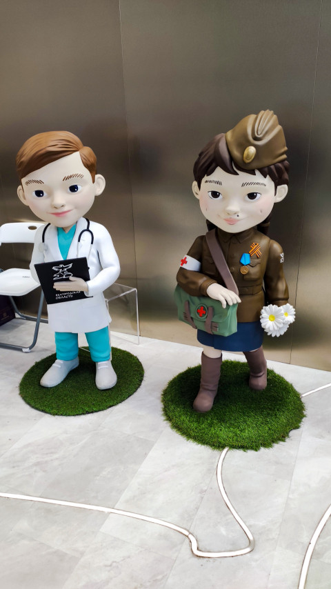Фигуры медика и девочки в форме на стенде Белгородской области
